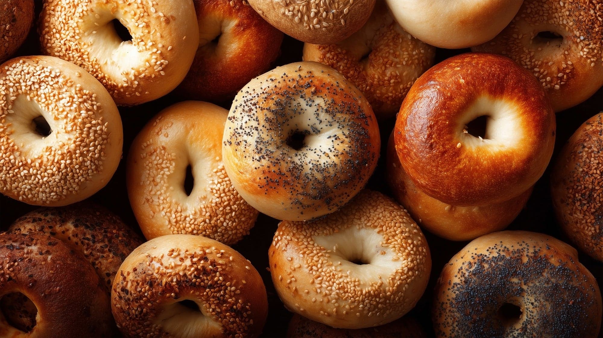 A pile of fresh sesame, poppy and plain bagels